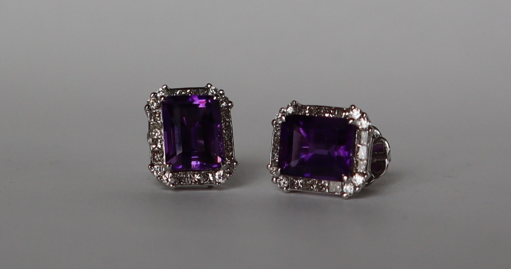 A pair of amethyst and diamond earrings each set with a step cut amethyst surrounded by twenty two
