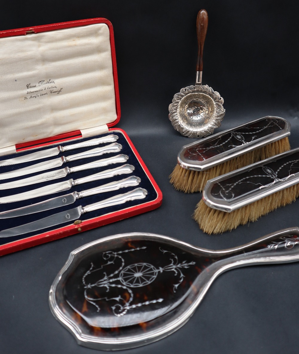 A silver and tortoiseshell mounted hand mirror together with two matching brushes,