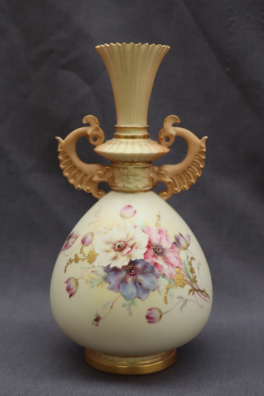 A Royal Worcester porcelain twin handled vase with a flared neck and scrolling handles,