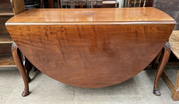 A mahogany gateleg dining table with an oval top on shell capped cabriole legs and cloven hoof feet