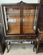 A 20th century mahogany display cabinet with glazed doors and glazed sides above two drawers on