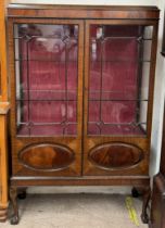 An Edwardian mahogany display cabinet with a domed top above glazed and panelled doors with glazing