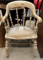 A smokers bow elbow chair with a horse shoe shaped back and turned spindles with a solid seat on