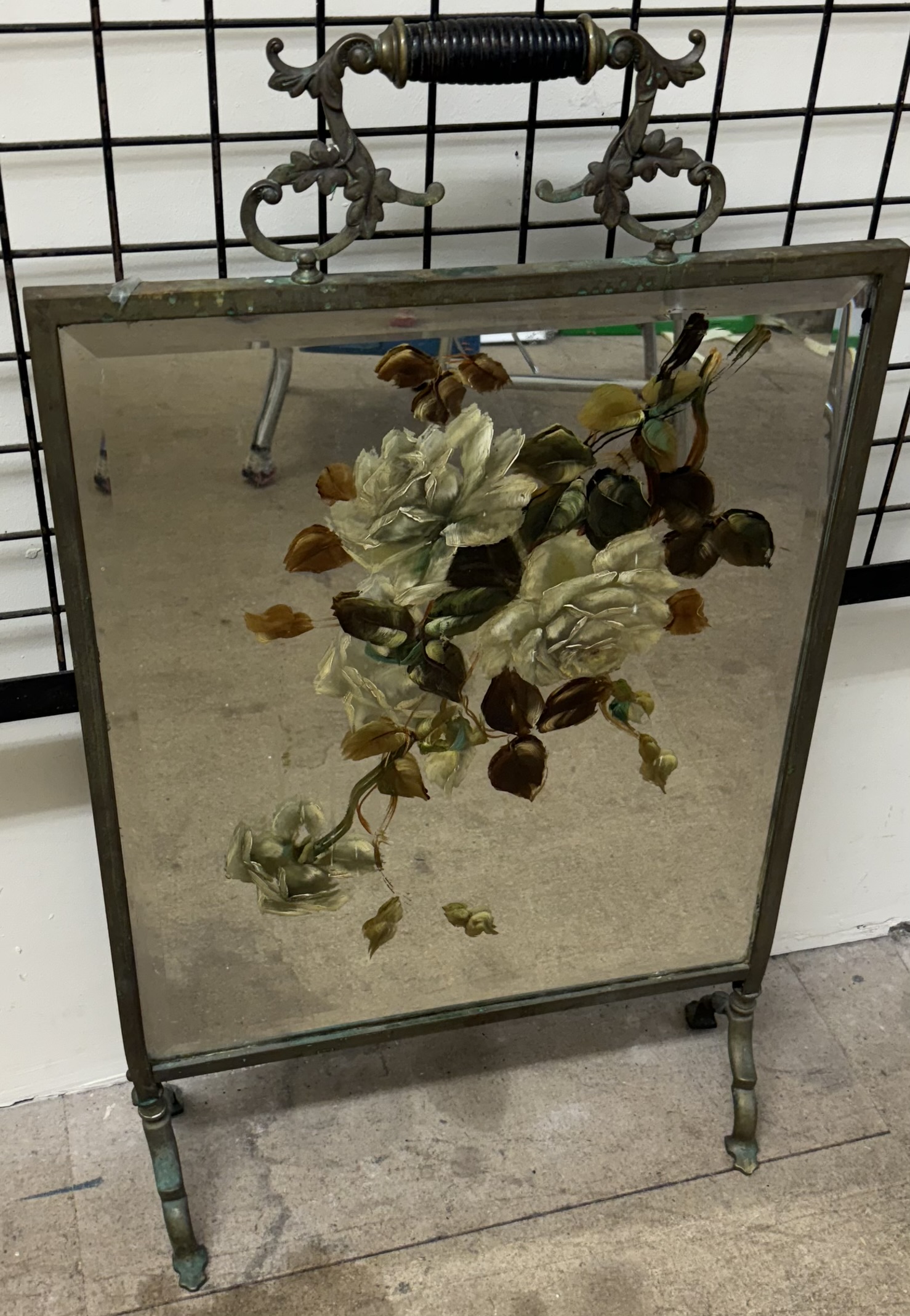 A brass framed floral painted mirrored firescreen