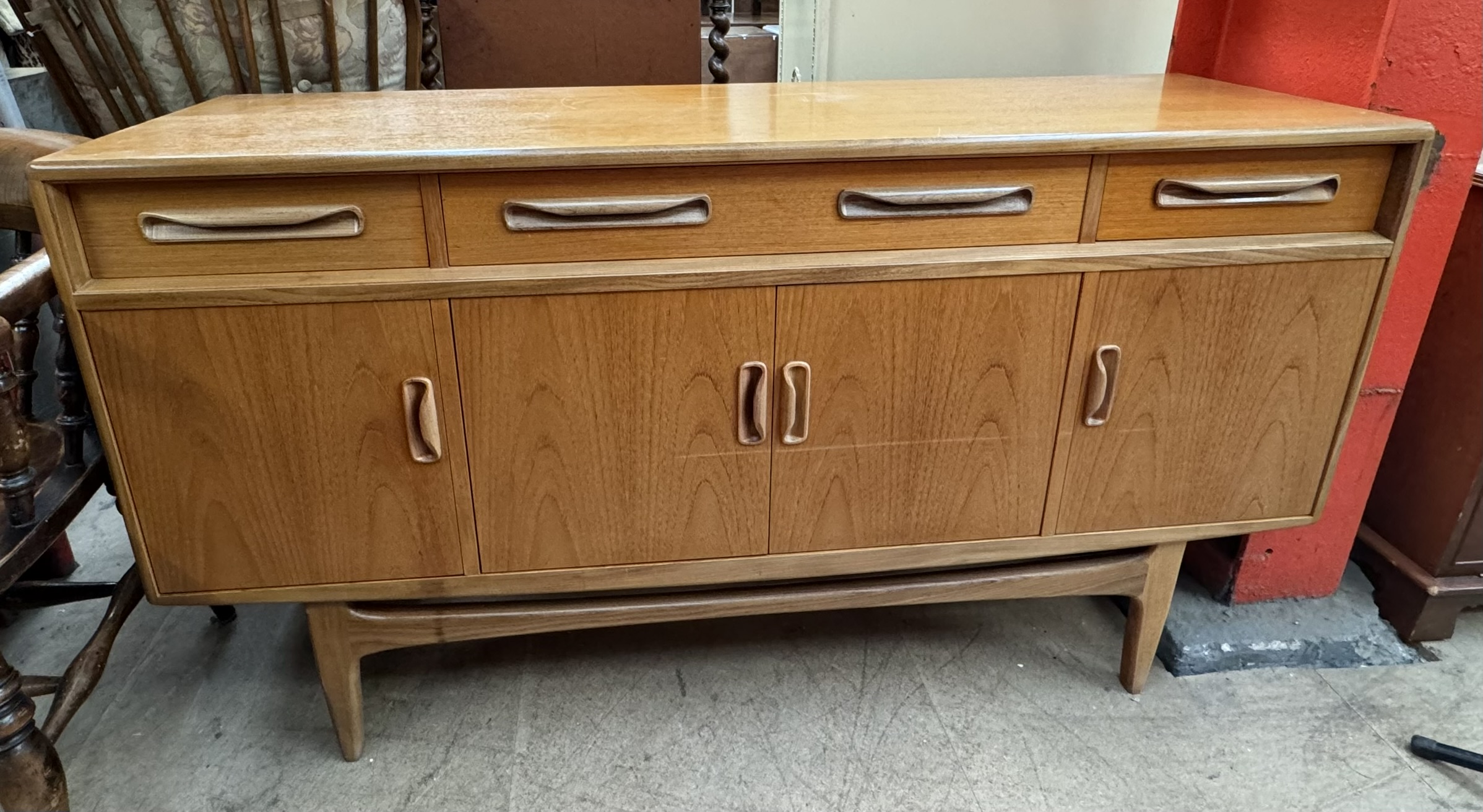A G-Plan teak sideboard with three drawers and four cupboards on tapering legs,