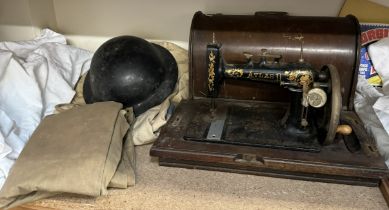 An Atlas sewing machine together with a military tin helmet,