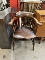 A smokers bow elbow chair with a spindle back and solid seat on turned legs