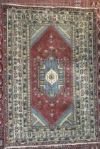 A large rug with a central blue ground medallion within a red field and numerous guard stripes