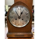 An oak mantle clock of pointed arched form with a silvered dial and Arabic numerals