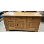A 20th century oak dresser base with a rectangular top above three drawers and three cupboards on