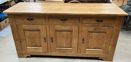 A 20th century oak dresser base with a rectangular top above three drawers and three cupboards on