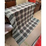A Welsh blanket with a green ground and geometric patterns in black and white