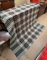 A Welsh blanket with a green ground and geometric patterns in black and white