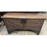 An 18th century oak coffer with a planked moulded top above a carved front on stiles 106cm long x