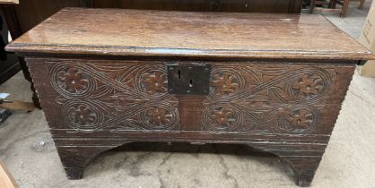 An 18th century oak coffer with a planked moulded top above a carved front on stiles 106cm long x