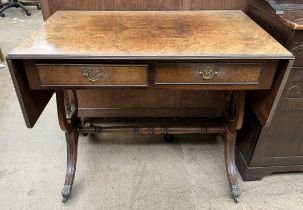 A reproduction walnut sofa table with a rectangular top with drop flaps above two drawers on lyre