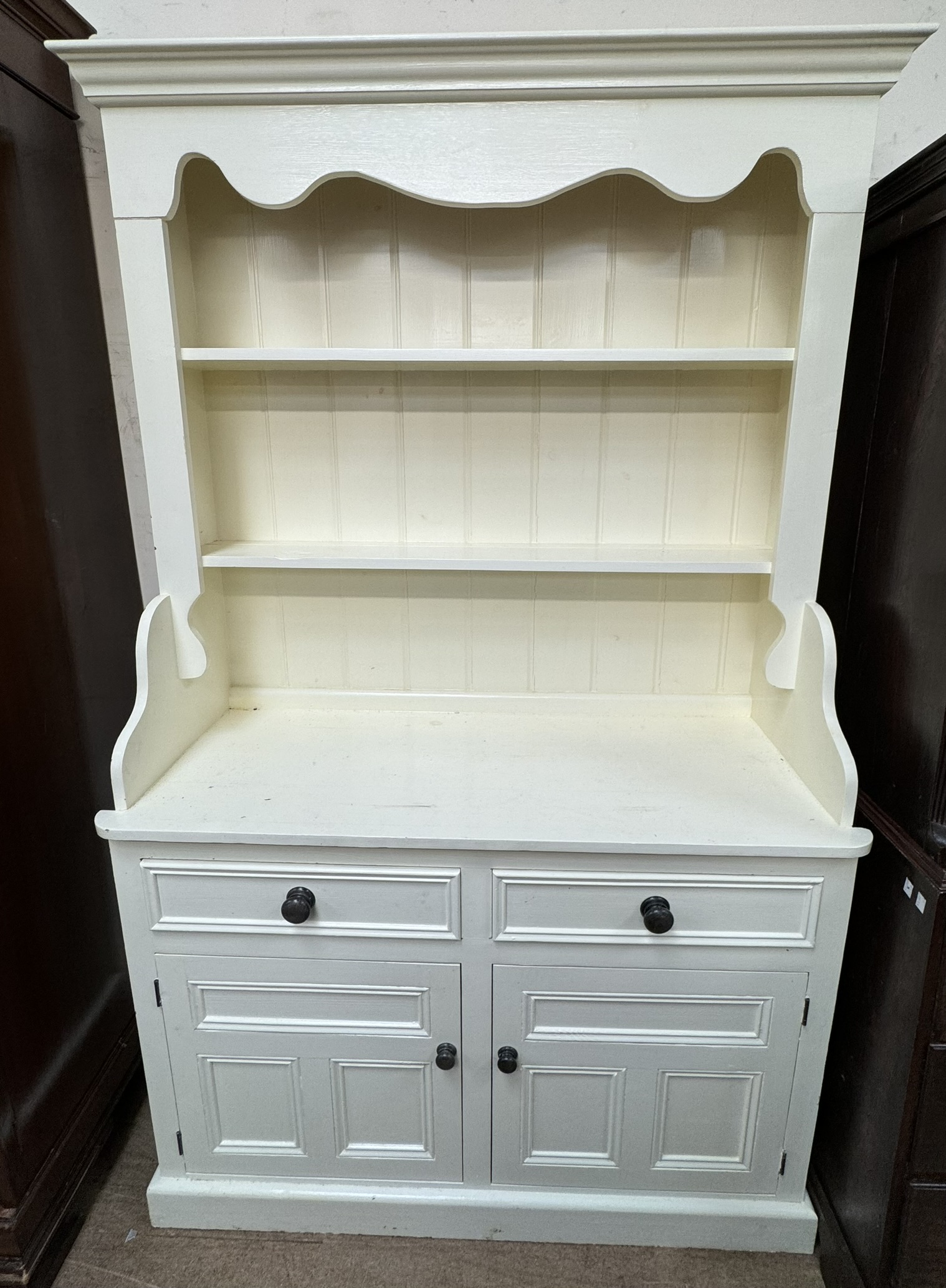 A cream painted pine dresser with a moulded cornice and two shelves the base with two drawers and