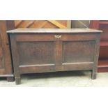 An 18th century oak coffer with a planked rectangular top above a two panel front on stiles