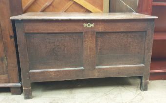 An 18th century oak coffer with a planked rectangular top above a two panel front on stiles