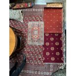 A small rug with a central red ground and geometric decoration to multiple guard stripes,