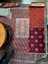A small rug with a central red ground and geometric decoration to multiple guard stripes,