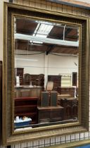 A large gilt framed wall mirror with a fluted and floral border,