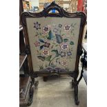 A 19th century walnut framed fire screen with a leaf moulded scrolling handle to the top,