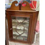 A 19th century mahogany hanging corner cupboard with a broken swan neck pediment and a glazed door