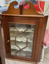 A 19th century mahogany hanging corner cupboard with a broken swan neck pediment and a glazed door