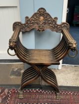 An Italian Savonarola chair with a carved back rail,