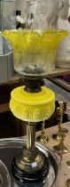 A Victorian oil lamp with a brass column and lemon yellow glass reservoir and graded glass shade