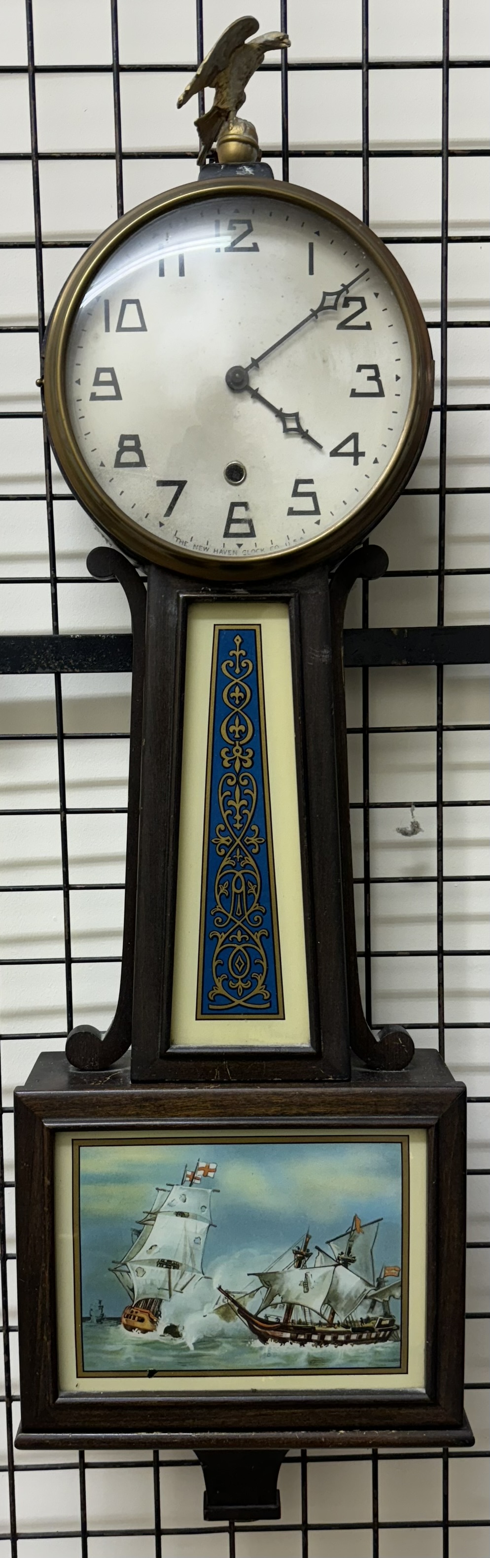 The New Haven Clock Co wall clock with a silvered dial and Arabic numerals with an eagle surmount,