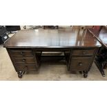 A 20th century dark teak desk with a rectangular top and five drawers on square turned legs