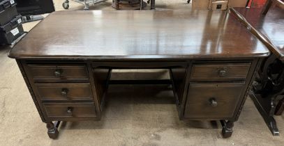 A 20th century dark teak desk with a rectangular top and five drawers on square turned legs