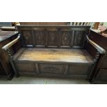 A late 19th century oak settle with a five panel carved back above a box seat on turned legs