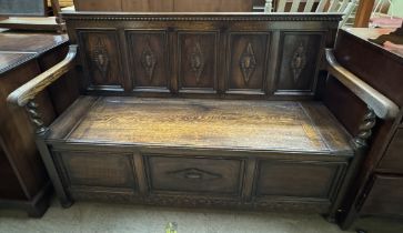 A late 19th century oak settle with a five panel carved back above a box seat on turned legs