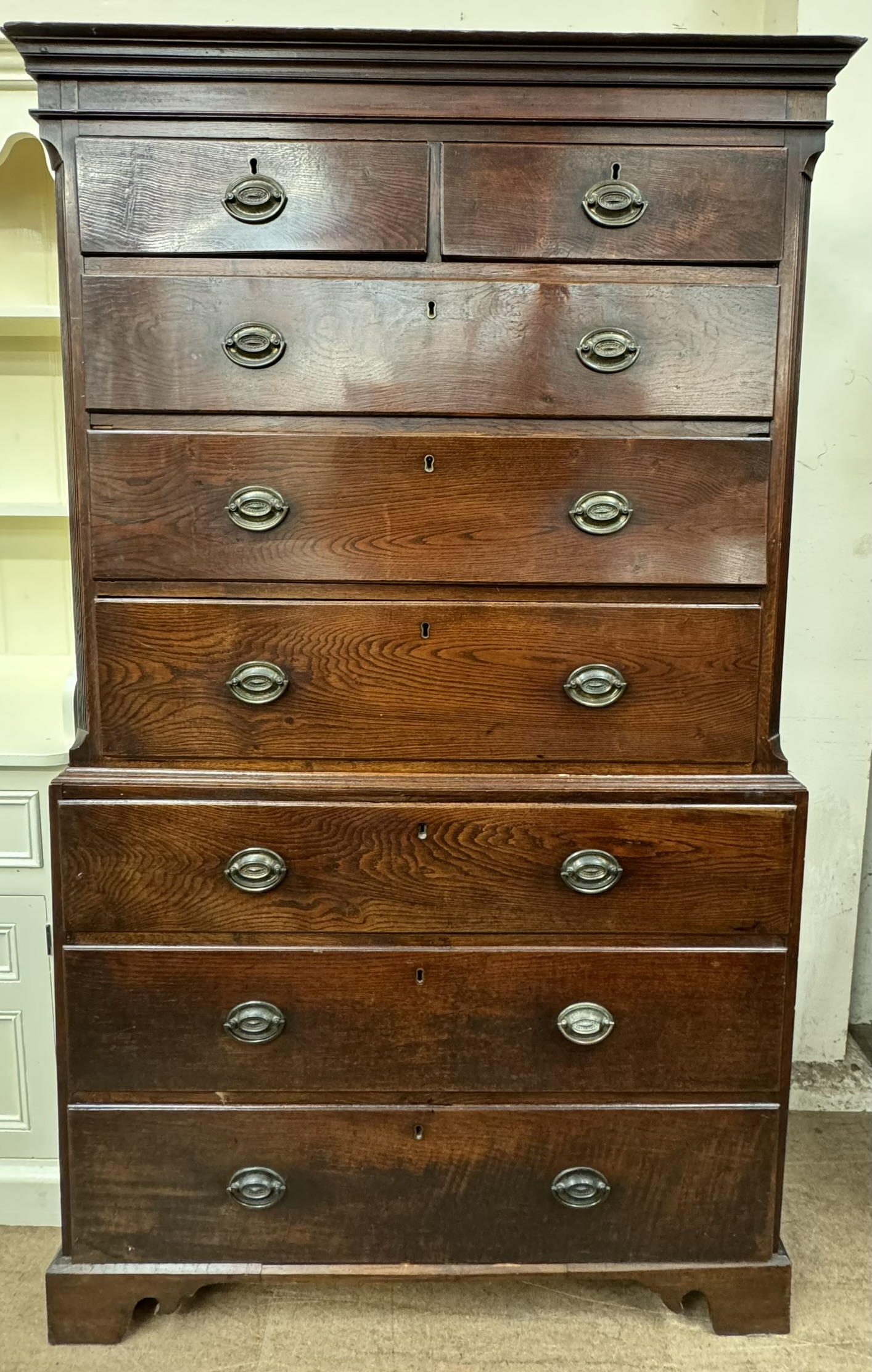An 18th century oak chest on chest with a moulded cornice above two short and six long graduated
