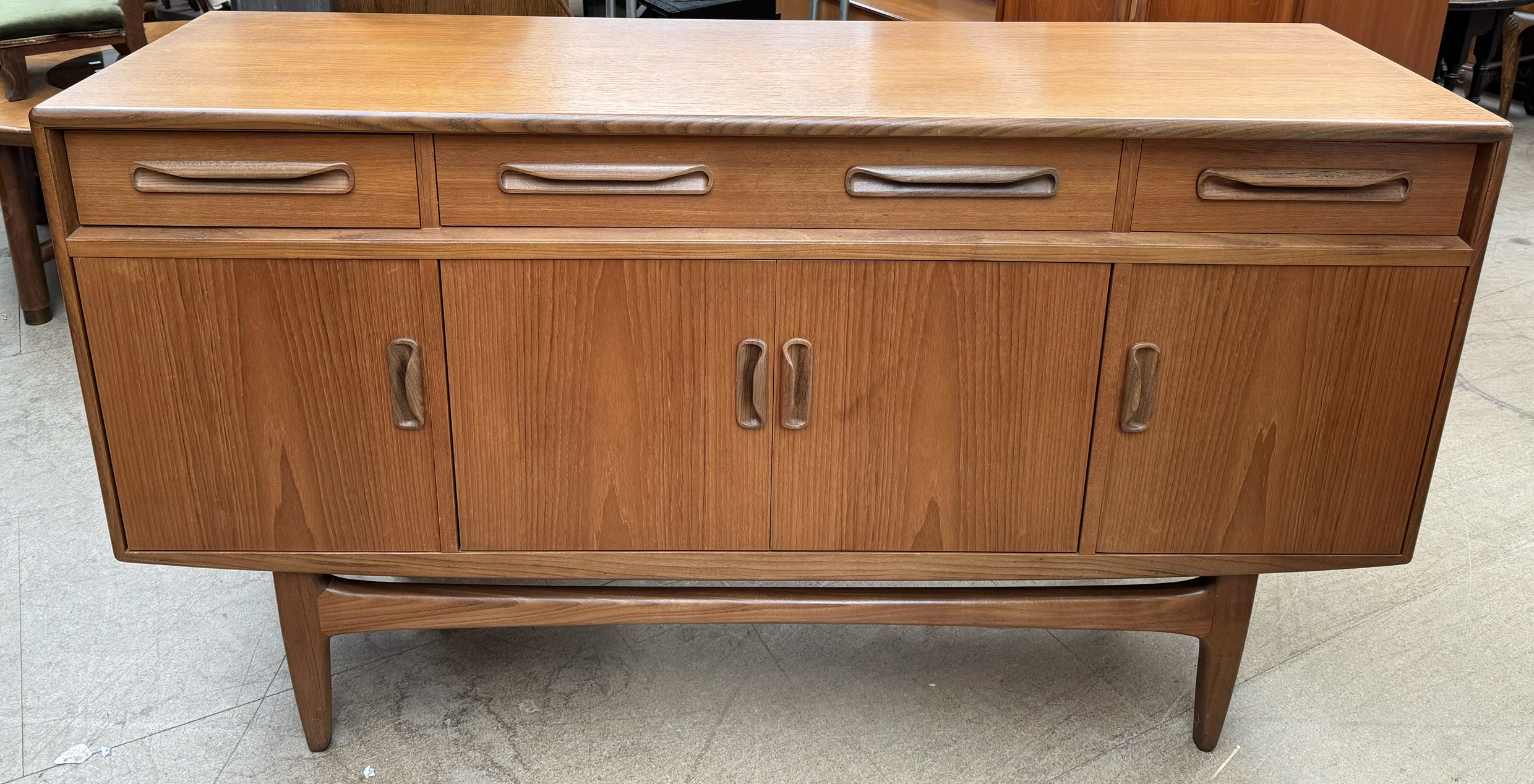 A mid 20th century teak G-Plan sideboard with three drawers and four cupboards on tapering legs,