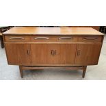 A mid 20th century teak G-Plan sideboard with three drawers and four cupboards on tapering legs,