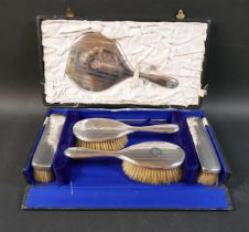 An Edwardian silver backed dressing table hair brush set, with hand mirror, 27cm, two hair brushes
