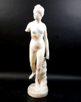 A white marble statue, modelled as a Greek or Roman Goddess, standing nude on her left foot, 15 by