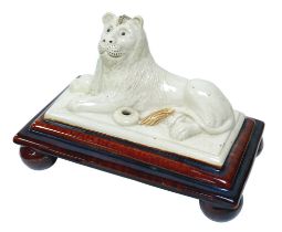 An 18th century Staffordshire spill vase with recumbent lion, treacle glazed base raised upon four