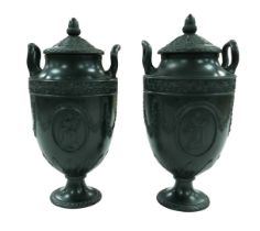 A pair of mid 19th century Wedgwood black basalt twin-handled urns and covers, each decorated in
