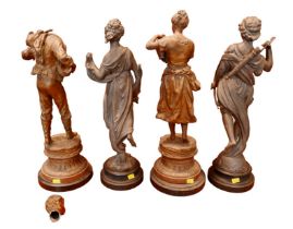 Two pairs of spelter sculptures, modelled as standing figures, on circular bases, 44 and 46cm