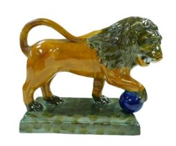 A 18th century or later Staffordshire figurine modelled as a Medici lion, with for paw resting