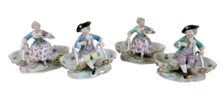 A group of four 19th century Meissen salts, modelled as figures in 18th century attire sitting on