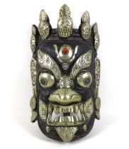 A Nepalese carved wooden mask, white metal mounted, depicting the Wrathful Bhairava, 22 by 34 by