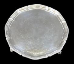 A George V silver tray, with decorative scalloped edge, engraved centre, raised on three ball and
