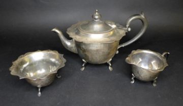 An Edwardian silver three piece tea set, comprising milk jug, teapot with ebonized wooden handle and