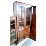 A 1930s oak bookcase cabinet with a two door glazed top above a two door base